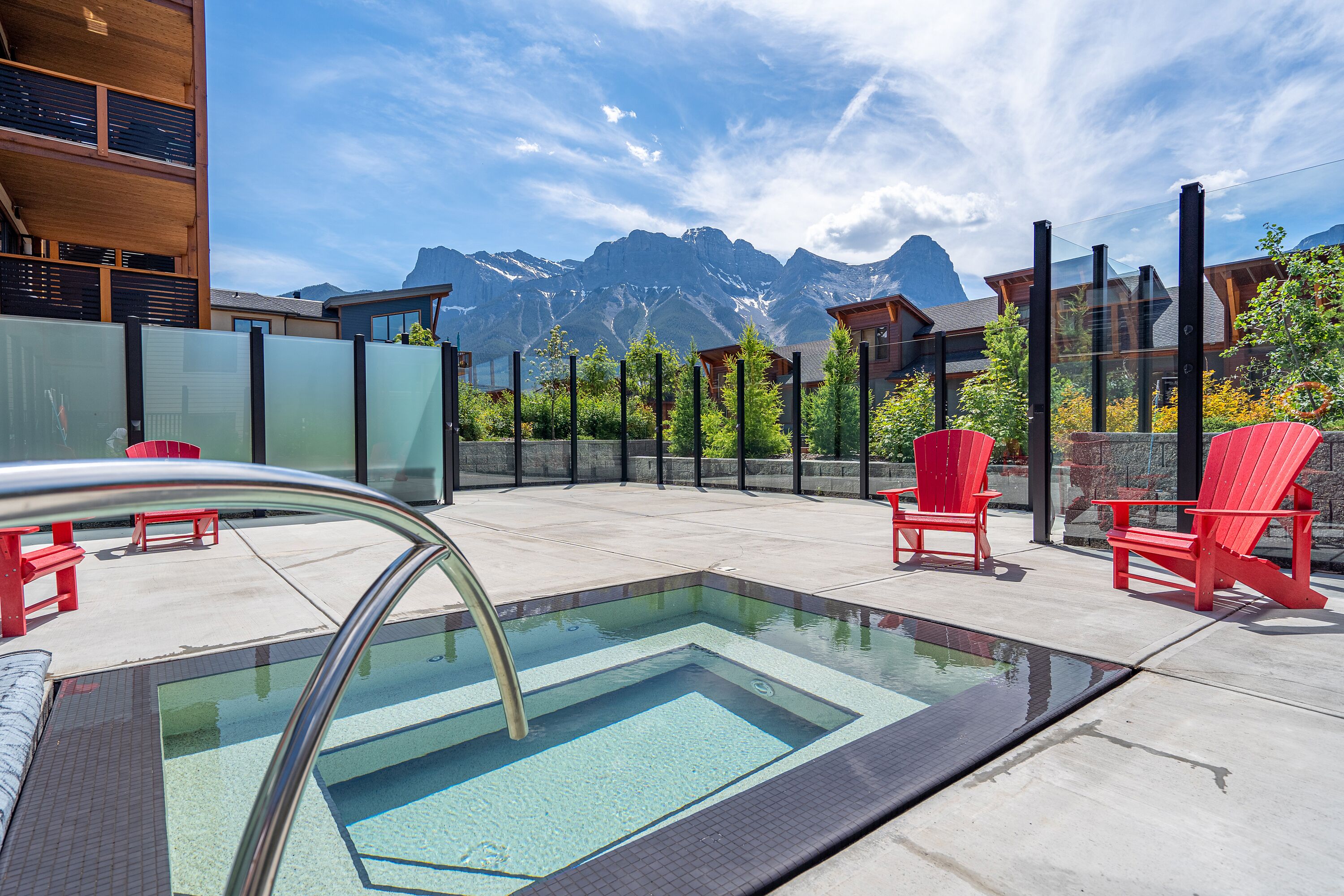 Une piscine sur le toit, avec des chaises rouges et une vue sur les montagnes.