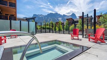 Une piscine sur le toit, avec des chaises rouges et une vue sur les montagnes.