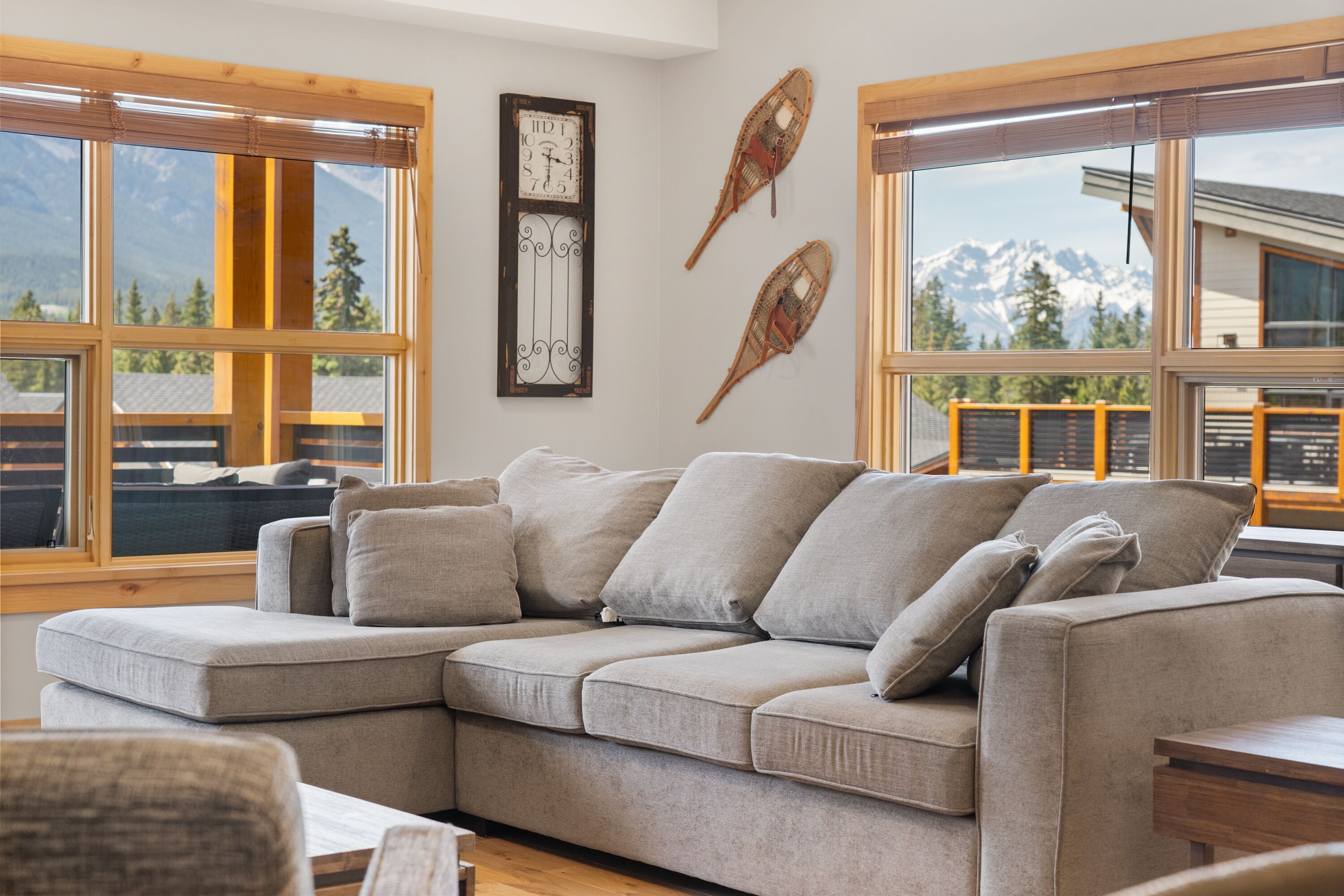Un salon moderne avec un canapé d’angle, de grandes fenêtres et une vue sur les montagnes.