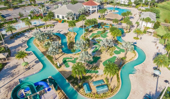 Eine Vogelperspektive zeigt einen Urlaubsort mit mehreren Schwimmbecken, einer Wasserrutsche und einem Golfplatz.
