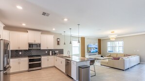 A modern kitchen with white cabinets, stainless steel appliances, and a central island.