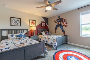 Ein Schlafzimmer mit zwei Betten, einem Deckenventilator und einem großen Wandgemälde mit Captain America.