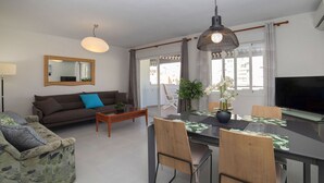A modern living room with a sofa, coffee table, dining table, chairs, and a TV. - Beautiful apartment for 6 people with pool, A/C, WIFI, TV and terrace (Calpe)