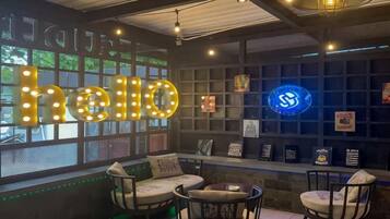 A cozy seating area with illuminated 'hello' letters, a blue neon sign, and a wall with framed pictures and awards.