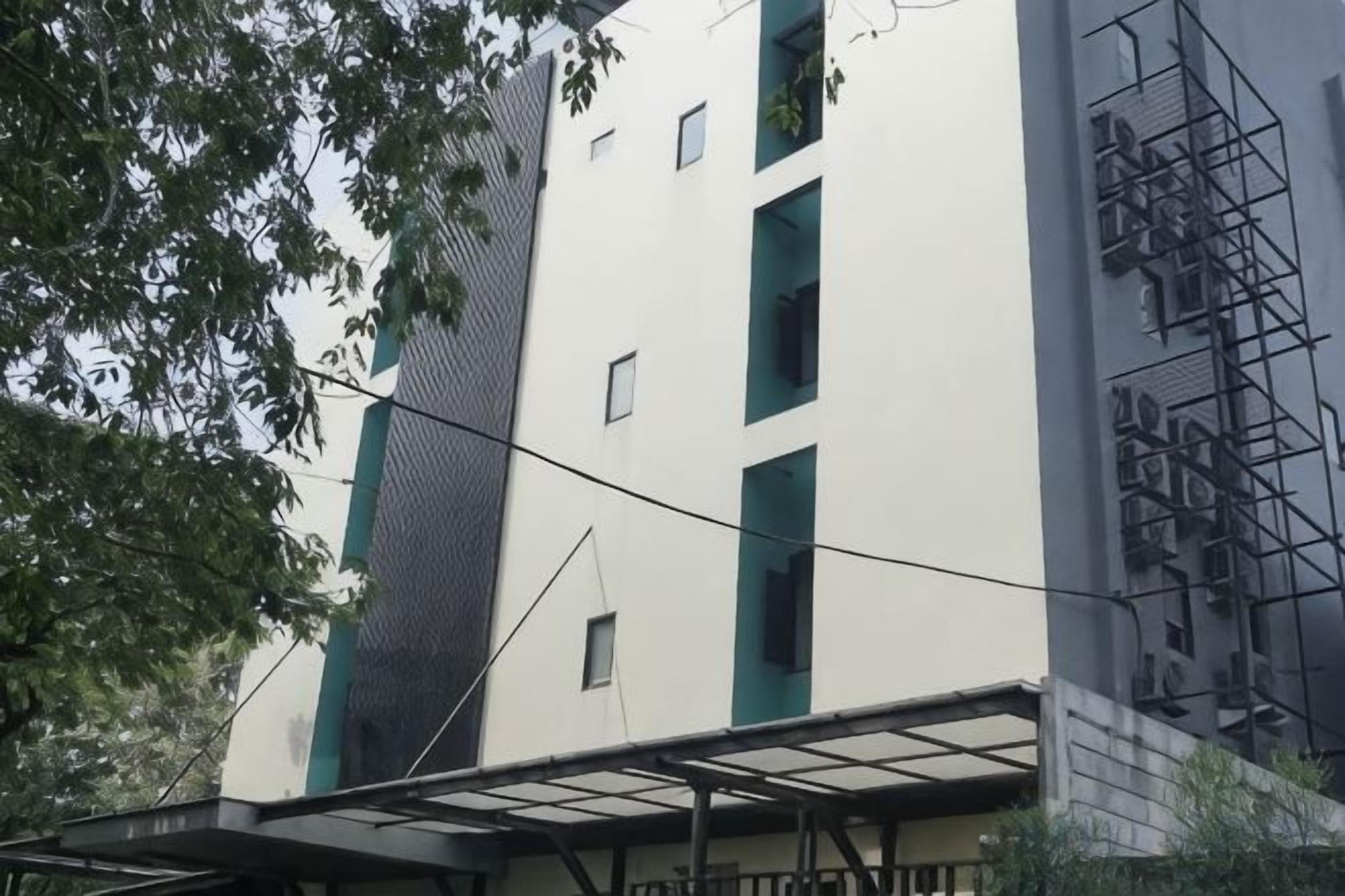 A multi-story building with a flat facade, a covered entrance, and a fire escape on the right side.