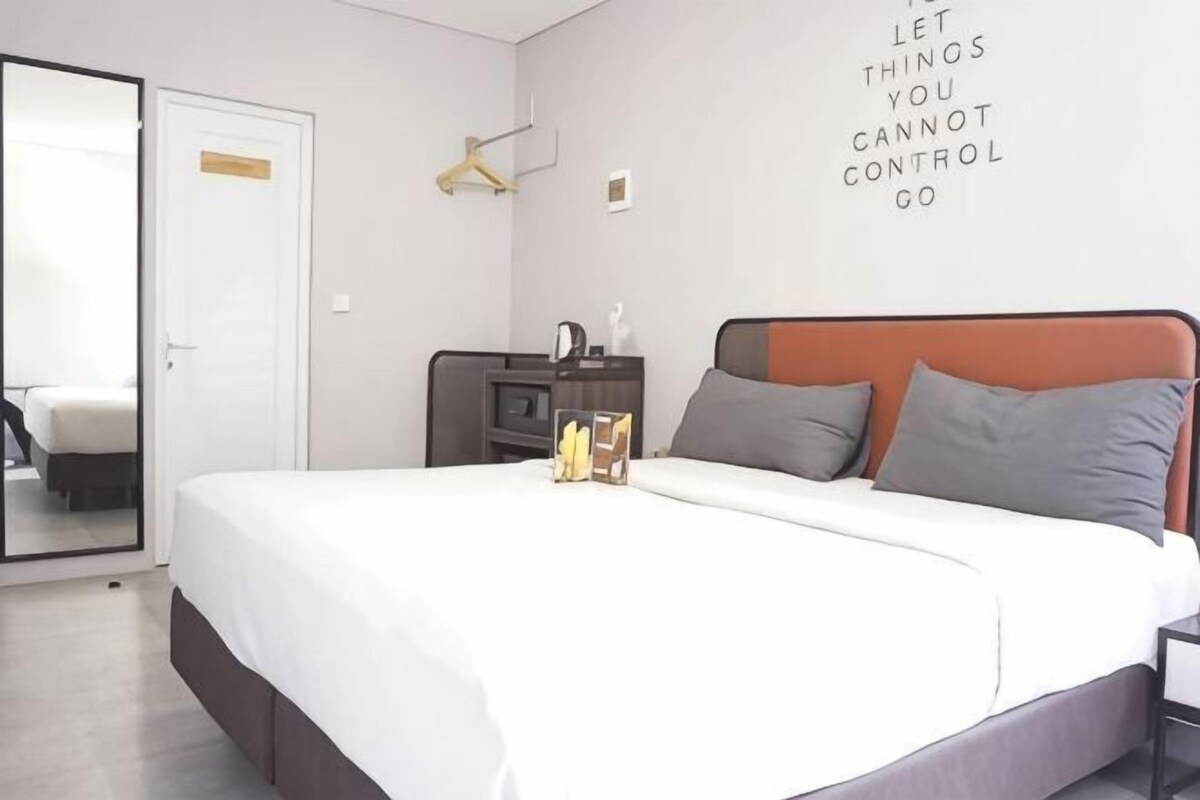 Een slaapkamer met een bed, een dressoir, een spiegel en een motiverende quote op de muur.