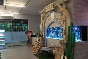 A children's play area with a cowboy statue, a blue wall with a desert scene, and a cactus decoration. - Sambina Prime (West Jakarta)