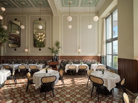 A restaurant with round tables, chairs, and a patterned floor.