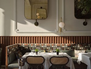 A dining area with a table set for two, a sofa, and a patterned wall. - ON Residence (Thessaloniki)