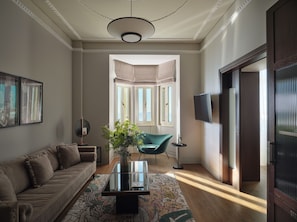 A living room with a sofa, a coffee table, a TV, and a view of the outside. - ON Residence (Thessaloniki)