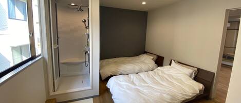 Un dormitorio con dos camas, ducha y ventana.
