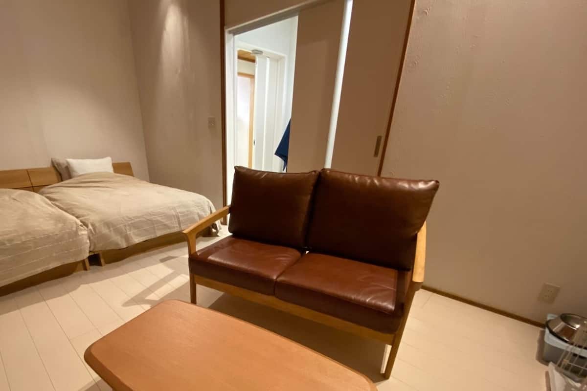 A bedroom with a bed, a brown leather sofa, and a wooden table.