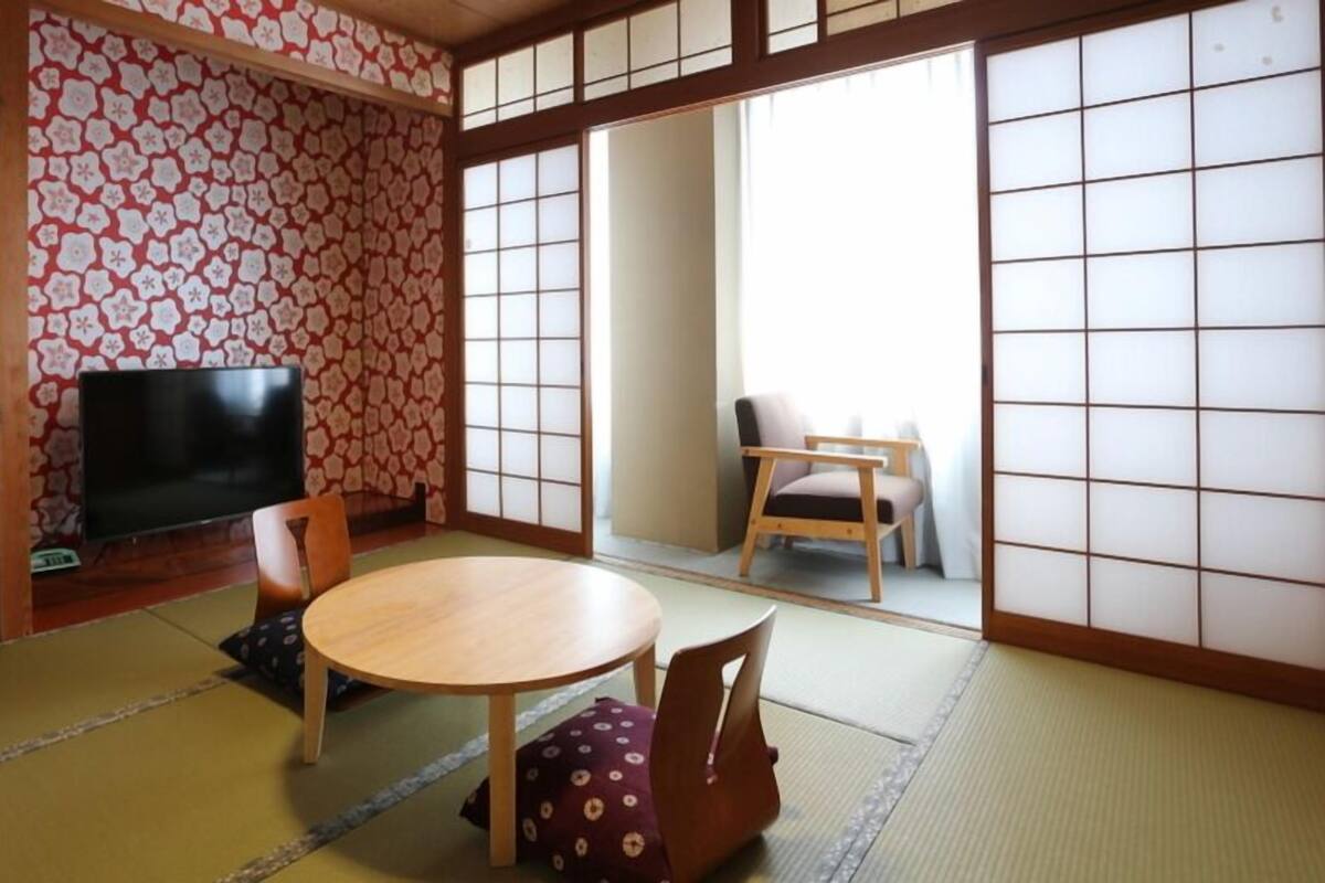 Una habitació japonesa tradicional amb tatami, una taula baixa, una televisió i portes corredisses.