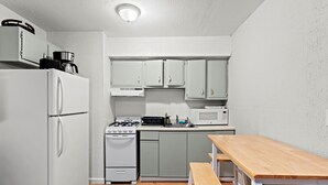 Eine kleine Küche mit Kühlschrank, Herd, Mikrowelle und Schränken.