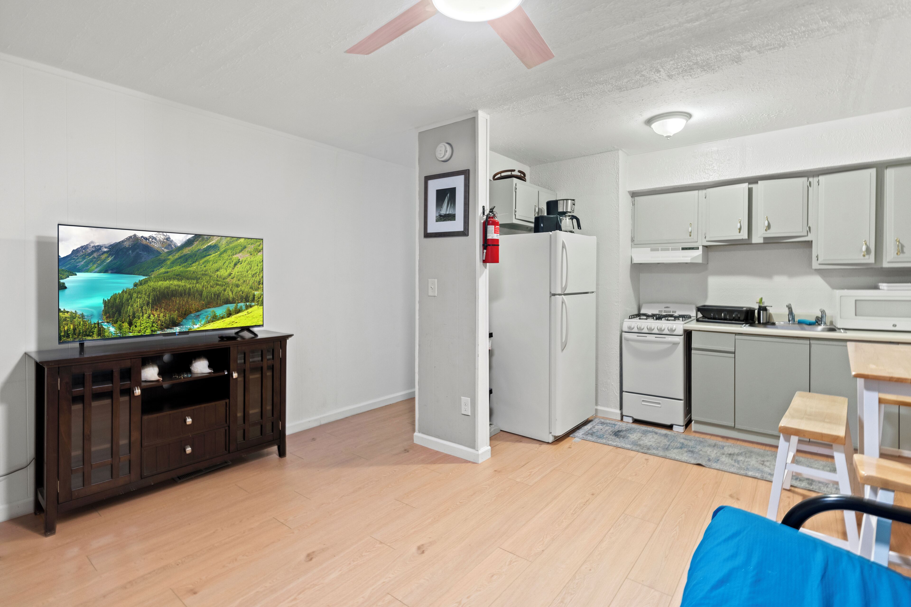 Un salon moderne doté d’un téléviseur à écran plat, d’un meuble de rangement en bois et d’un ventilateur de plafond.