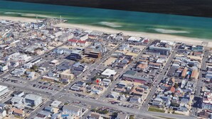 Eine Vogelperspektive auf eine Küstenstadt mit einem Straßennetz, Häusern, einem Strand und einem Leuchtturm.