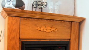 Una chimenea de madera con puerta de vidrio, un soporte metálico decorativo y una cámara encima.