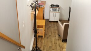 Una escalera que lleva a una habitación con piso de madera, una pequeña mesa con un jarrón y un armario.