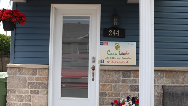 Una casa con fachada azul, puerta blanca y un cartel con el número 244.