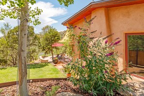 A patio area with outdoor furniture, a pergola, and a variety of plants.