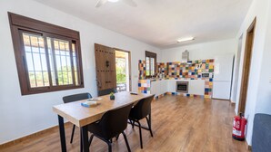 A spacious kitchen with a colorful backsplash, a dining area with a wooden table and chairs, and a ceiling fan. - Cortijo Jimena by Solset (Málaga)