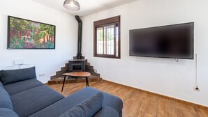 A modern living room with a sofa, a fireplace, a TV, and a painting on the wall. - Cortijo Jimena by Solset (Málaga)