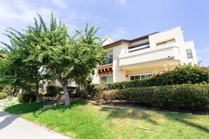 A modern two-story house with a well-maintained lawn and a large tree in the front yard.