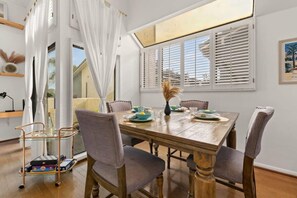 A dining area with a wooden table set for four, surrounded by cushioned chairs.