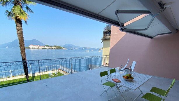 A balcony with a table, chairs, and a view of the sea and mountains. - Stone apartment with lake view in Baveno (Baveno)