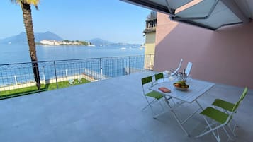 Ein Balkon mit Tisch, Stühlen und Blick auf das Meer und die Berge.