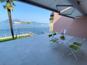 A balcony with a table, chairs, and a view of the sea and mountains. - Stone apartment with lake view in Baveno (Baveno)