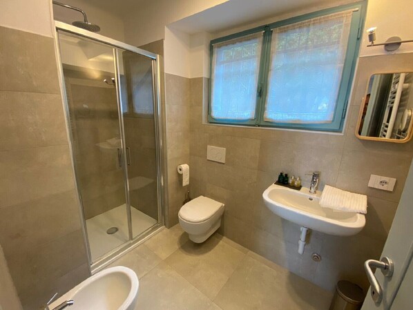 A bathroom with a glass-enclosed shower, a toilet, a sink, and a bidet. - Stone apartment with lake view in Baveno (Baveno)