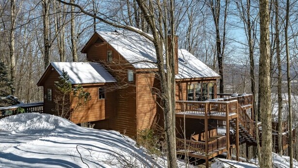 A wooden cabin with a balcony, surrounded by trees and snow. - Bear Ridge - Valley Views, Hot Tub, Dog Friendly (Davis)