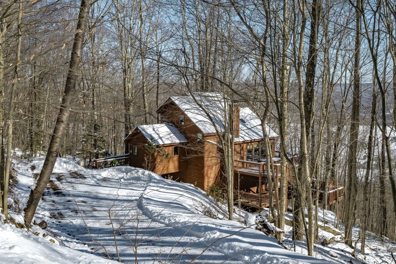 Eine Holzhütte mit einer Veranda, umgeben von schneebedeckten Bäumen.