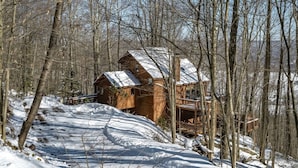 A wooden cabin with a deck, surrounded by snow-covered trees. - Bear Ridge - Valley Views, Hot Tub, Dog Friendly (Davis)