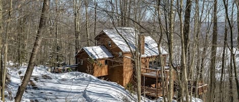 Eine Holzhütte mit einer Veranda, umgeben von schneebedeckten Bäumen.