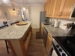 A kitchen with granite countertops, wooden cabinets, a dishwasher, a stove, and a refrigerator.