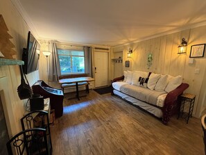 A cozy room with a wooden floor, a white sofa, a small table, and a bench.