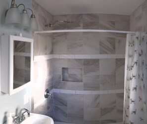 Une salle de bain dotée d’une douche à espace incurvé, d’un lavabo avec un miroir et d’un rideau de douche à motifs animaliers.
