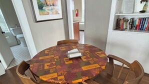 Una mesa de comedor redonda de madera con mantel estampado, rodeada por cuatro sillas de madera.