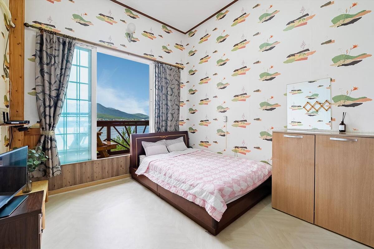 Un dormitorio con cama, televisión y vista al mar.