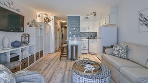 Un espacio habitable compacto con kitchenette, un sofá, un televisor y elementos decorativos.