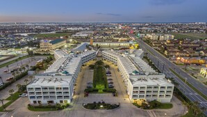 Un hotel grande y moderno con un patio central, varios estacionamientos y vistas del paisaje urbano al atardecer.