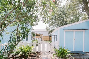 Enjoy a serene outdoor space with a deck, lush plants, and a charming wooden shed.