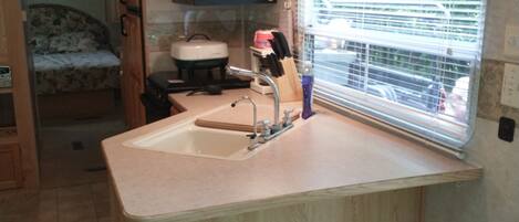 A compact kitchen with a sink, a toaster, and a window with blinds.