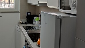 Una cocina compacta con armarios blancos, un microondas, una estufa y un refrigerador.