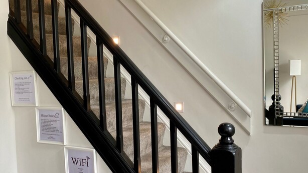 A staircase with black balusters and a handrail, carpeted steps, and a wall-mounted sign indicating WiFi availability.