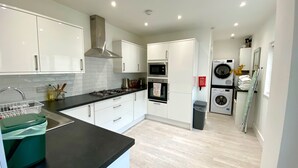 A modern kitchen with white cabinets, a black countertop, stainless steel appliances, and a laundry area with a washing machine and dryer.