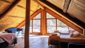 A spacious attic bedroom with large windows, wooden beams, a sofa, and a bed. - Girraween Country Inn (Eukey)