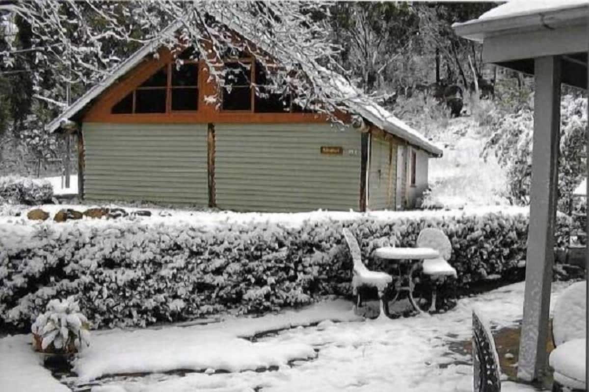 Un edificio cubierto de nieve con techo inclinado y ventana de madera.